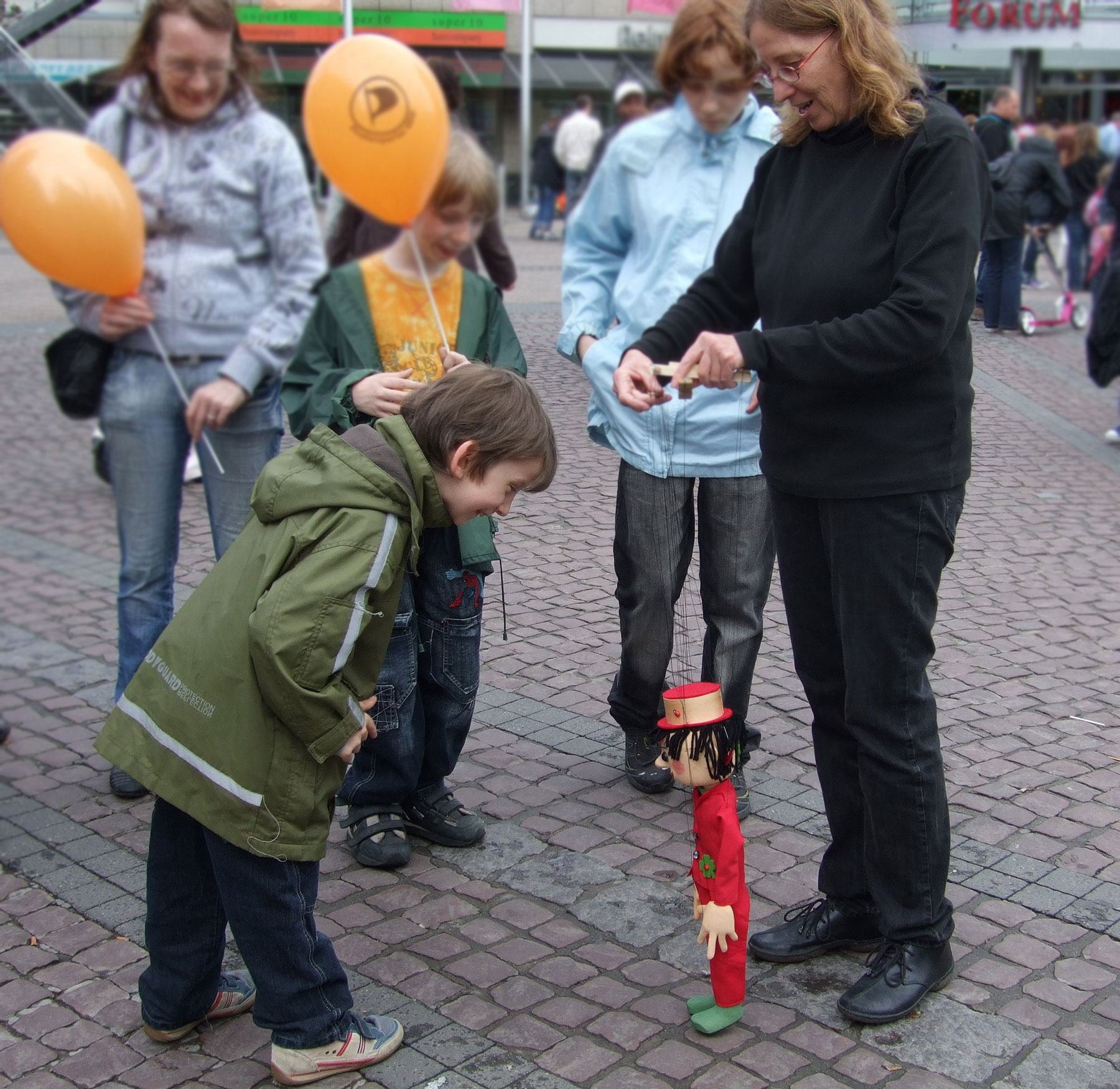 Foto: Dorothee Wellfonder mit der Marionette Fidibus, erfreut vor einem Einkaufszentrum die Fußgänger